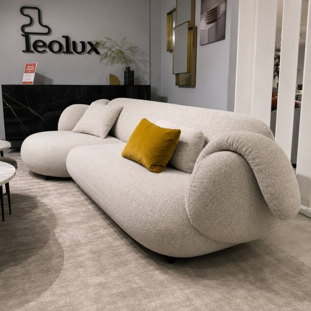 Leolux Pulla salon met afgeronde armleuningen en sculpturale vormen in lichte stofbekleding, toonzaalmodel bij Verberckmoes Sint-Gillis-Waas.