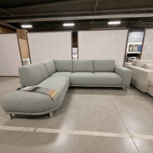 Vooraanzicht van de Maxfurn Lincoln hoekbank in stof Sneak sky met losse rugkussens en ottomane links