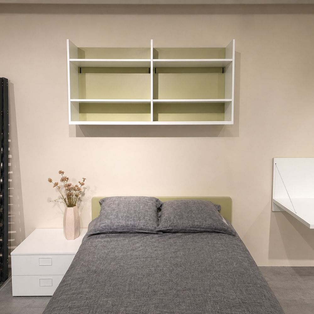 Vooraanzicht van Nardi bed met olijfgroen hoofdbord, wit nachtkastje en open wandboekenrek, toonzaalmodel Sint-Gillis-Waas – Verberckmoes