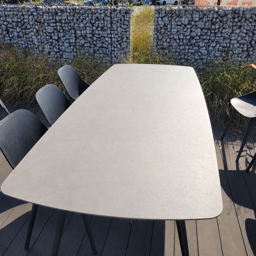 Bovenaanzicht van het bootvormige cementgrijze keramische tafelblad van de Jati Kebon Amazone tuintafel als terrasmodel in Temse