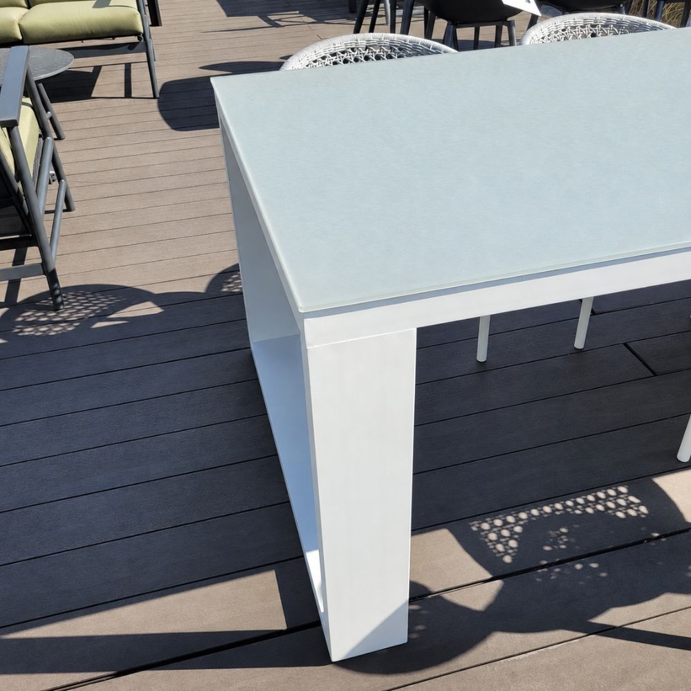 Detail van het lichtgrijze glazen tafelblad van 10 mm en het wit mat aluminium onderstel van de Jati Kebon Linate tuintafel als terrasmodel in Temse
